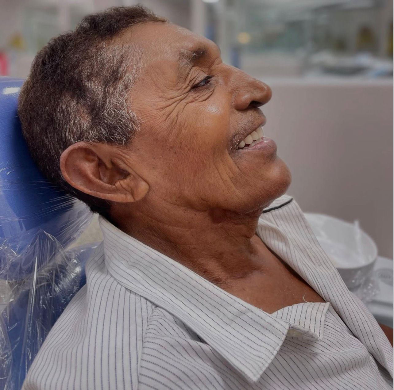 Paciente sorrindo na cadeira odontológica após o atendimento